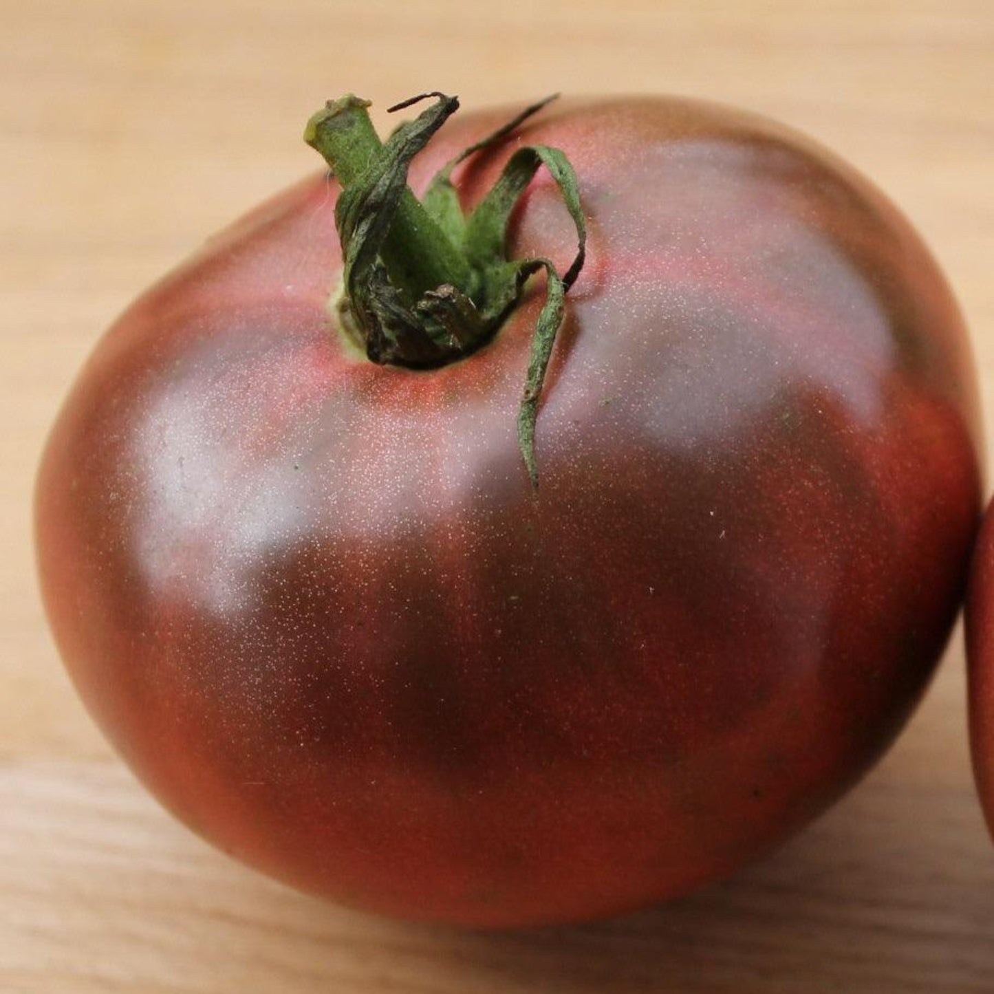 Cherokee Purple heirloom tomato with large dusky purple fruit on a wooden board