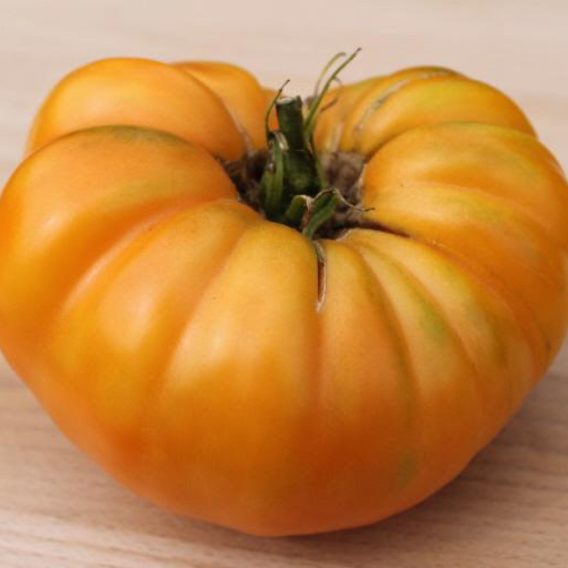 Large ripe Dr. Wyche's Yellow heirloom tomato on a wooden board