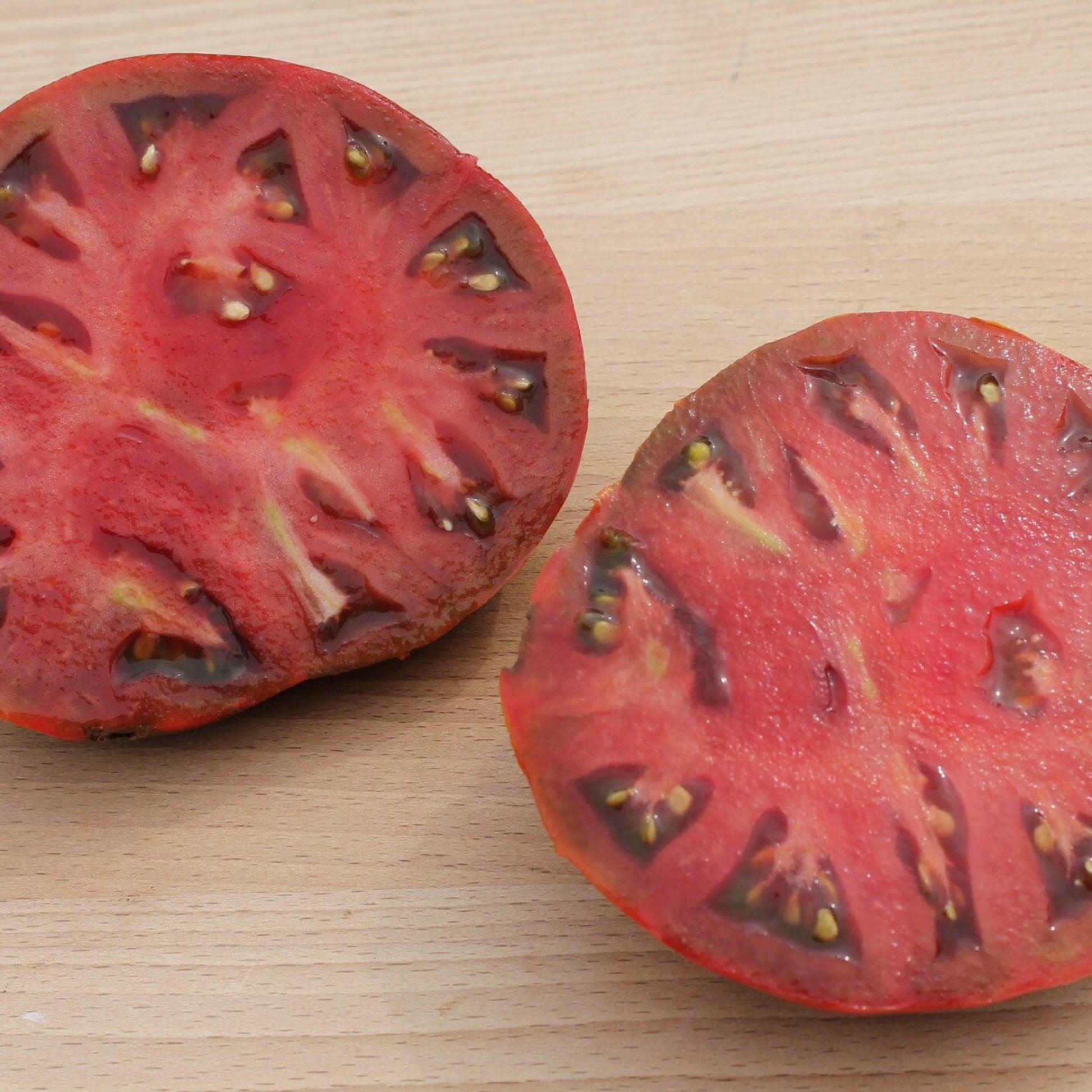 cherokee chocolate tomatoes sliced to show the interior with seeds.