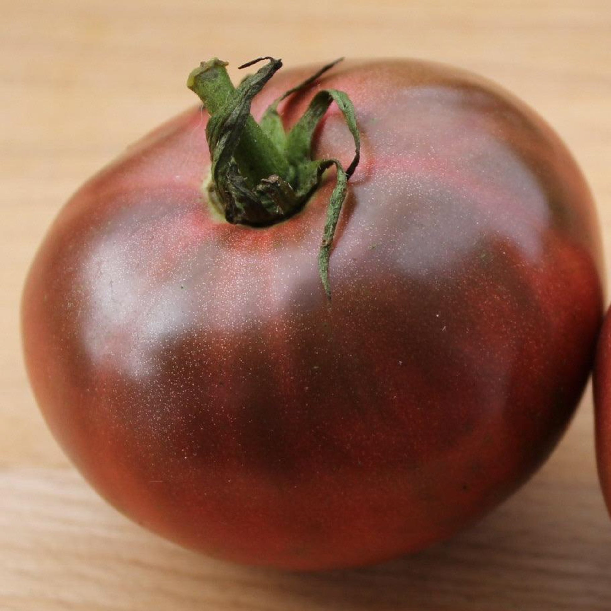 Cherokee Purple heirloom tomato with large dusky purple fruit on a wooden board